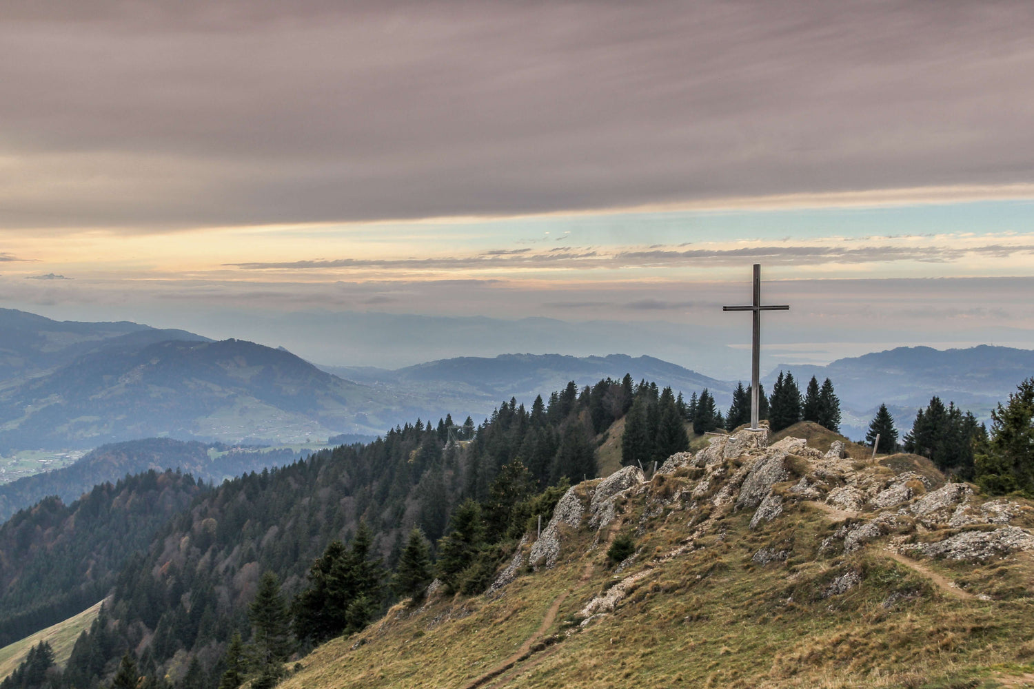 a cross stands on a rocky hill